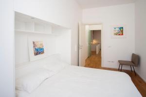 een witte slaapkamer met een wit bed en een stoel bij Gallery House in Perugia