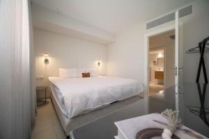 a white bedroom with a bed and a bathroom at סי סייד אילת - Sea Side Eilat in Eilat +63 photos