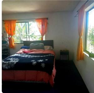 a bedroom with a bed and a window with orange curtains at Hare Maohi in Hanga Roa