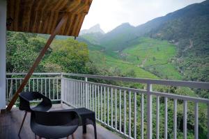 a balcony with a chair and a view of a valley at The TeaTree Munnar in Suryanelli