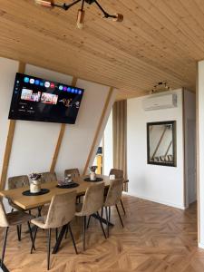 a dining room with a table and chairs and a tv at Catunu lupului village Cabana Monte Benito in Cotorăşti