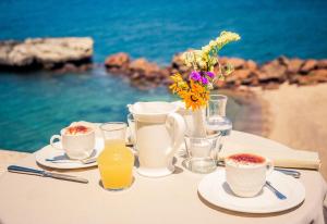 Hotel & SPA Riviera Castelsardo في كاستيلساردو: طاولة مع أكواب من القهوة و إناء من الزهور