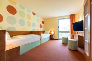 a hotel room with two beds and a tv at Hotel Holledau in Geisenhausen