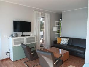 a living room with a couch and a tv at Lagrette Ferienwohnung am Hainer See in Neukieritzsch