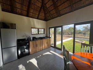a kitchen with a refrigerator and a table and some windows at Halali Wilderness Private Game Ranch in Hammanskraal