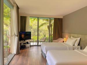 a hotel room with two beds and a television at Chốn Mộc - Cát Bà Resort in Cat Ba