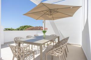 a table and chairs with an umbrella on a balcony at Complejo Los Drogos in Novo Sancti Petri