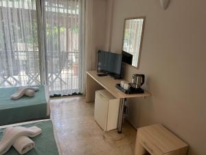 ein kleines Zimmer mit Fernseher und Schreibtisch mit Spiegel in der Unterkunft Avlu Hotel in Kemer