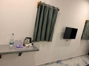 a room with green curtains and a tv on a wall at Restara Tower in Cochin