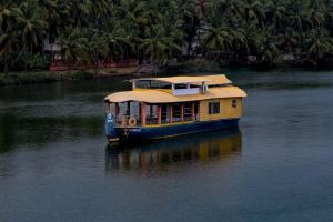 a yellow boat floating on a river with palm trees at Ezhimala cruise in Nīleshwar