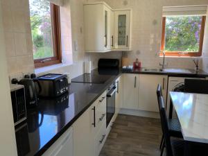 a kitchen with white cabinets and a black counter top at Daisy Cottage in Polegate