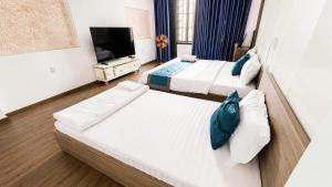 a hotel room with two beds and a flat screen tv at Mubee Homestay in Hue