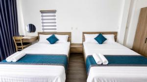 two beds in a hotel room with blue pillows at Mubee Homestay in Hue