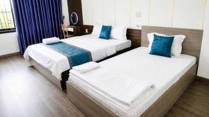two beds in a hotel room with blue pillows at Mubee Homestay in Hue
