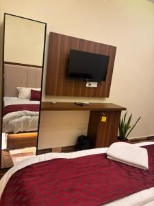 a bedroom with a mirror and a bed with a television at Hotel Gokulam Grand in Tenāli