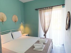 a bedroom with a bed with white pillows and a window at Villa Christina Sea Side A in Hanioti
