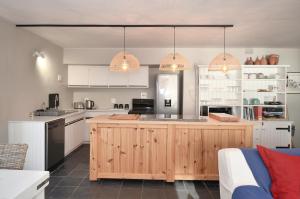 a kitchen with white cabinets and a wooden island at Voetjieshang in Yzerfontein +42 photos
