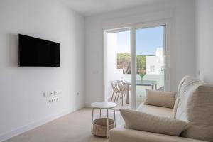 a white living room with a couch and a tv at Complejo Los Drogos in Novo Sancti Petri