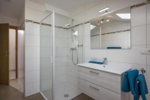 a white bathroom with a shower and a sink at Ferienwohnungen Dagn in Kössen +13 photos
