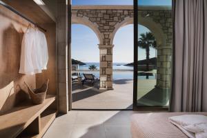 a bedroom with an open door with a view of the ocean at Alýria Sea Side Suites in Agios Nikolaos