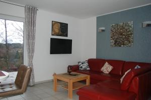 a living room with a red couch and a table at Behagliches Ferienhaus Zaunkönig -mit Kamin und Sauna- Blick über das romantische Bodetal in Tanne