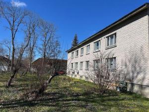 a large brick building with trees in front of it at Tamme apartment in Suuremõisa