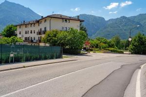 an empty street with a building and mountains in the background at Casa Rosa in Levico Terme