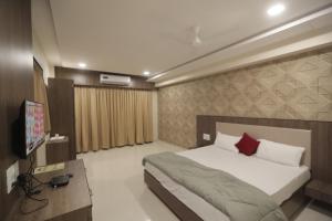 a bedroom with a bed and a flat screen tv at Royal Palace Hotel Surat Velanja in Sāyan