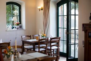 a dining room with a table and chairs and windows at Fliederhof Stücken Apartments bei Potsdam in Michendorf