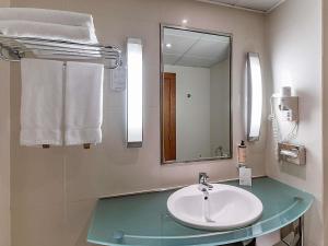 a bathroom with a sink and a mirror and towels at Hotel Mercure Lisboa in Lisbon