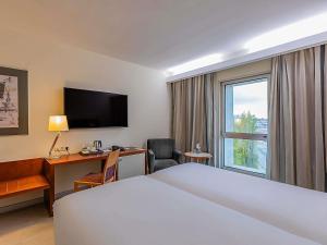 a hotel room with a bed and a desk and a window at Hotel Mercure Lisboa in Lisbon