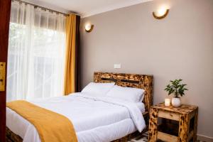 a bedroom with a bed with white sheets and a window at Pazuri Ark Gardens in Thika +10 photos