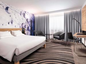 a hotel room with a bed and a desk and chairs at Novotel Poznan Centrum in Poznań +130 photos