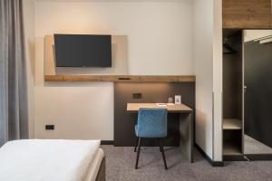 a room with a desk and a tv on a wall at Hotel zur Post in Hemmingen