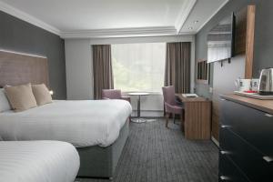 a hotel room with two beds and a table at Best Western Plough and Harrow Hotel in Birmingham