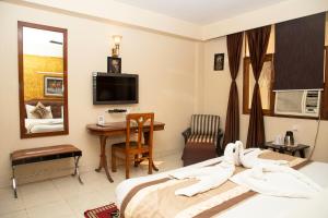 a hotel room with a bed and a desk and a television at Hotel Angel in Greater Noida +6 photos