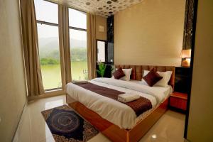 a bedroom with a large bed with a large window at hotel tripta ganga in Rishīkesh