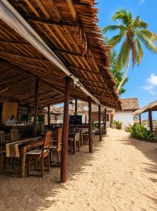 a restaurant with wooden tables and chairs on the beach at O'Sole Mio Assinie in Assinie