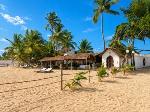 a building on a sandy beach with palm trees at O'Sole Mio Assinie in Assinie +60 photos