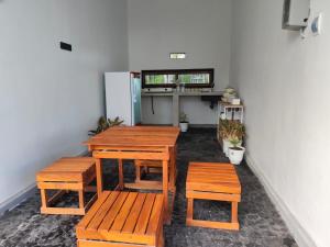 a group of wooden tables and benches in a room at FaqinHomestay in Pulau Sarang