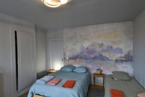 a bedroom with two beds and a painting on the wall at gîte MAELYSE in La Neuve-Lyre