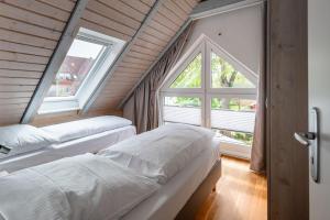 two beds in a room with a large window at Nordsee-Apartments Hinrichsen in Husum