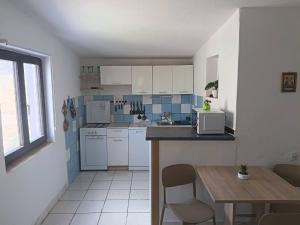 a kitchen with white cabinets and a table with chairs at Apatmani Čriček in Vlašići