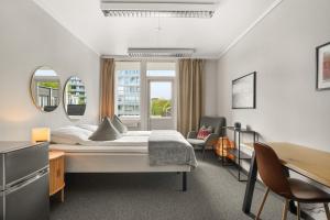 a bedroom with a bed and a desk and chairs at A11 Apartments in Ålesund