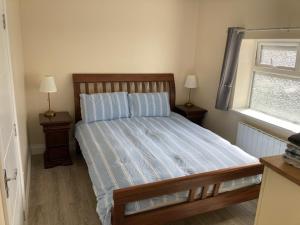 a bedroom with a bed with two night stands and a window at MeadowView Apt B -2 mins walk Carrigaline town -sleeps 4 - 2 Adults and 2 Kids in Carrigaline