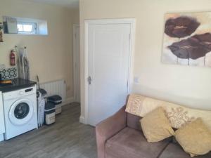 a living room with a couch and a washing machine at MeadowView Apt B -2 mins walk Carrigaline town -sleeps 4 - 2 Adults and 2 Kids in Carrigaline