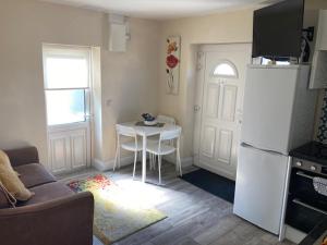 a living room with a table and a white refrigerator at MeadowView Apt B -2 mins walk Carrigaline town -sleeps 4 - 2 Adults and 2 Kids in Carrigaline