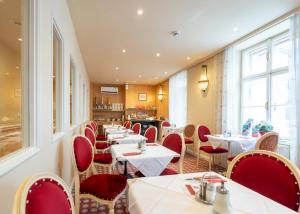 a restaurant with white tables and red chairs at Aviano Boutique Hotel in Vienna