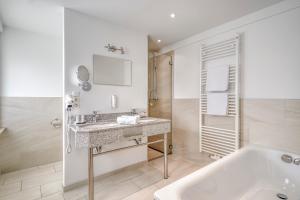 a bathroom with a sink and a bath tub at Strandgrün Golf- & Spa Resort in Timmendorfer Strand +74 photos