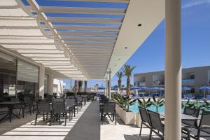 an outdoor patio with tables and chairs and a pool at Rethymno Village in Platanes